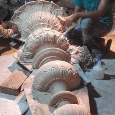 Artisans finishing a molded shell-shaped ornament