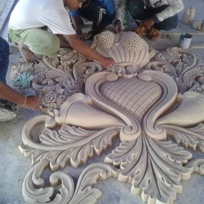 Artisans finishing a large molded floral scroll motif