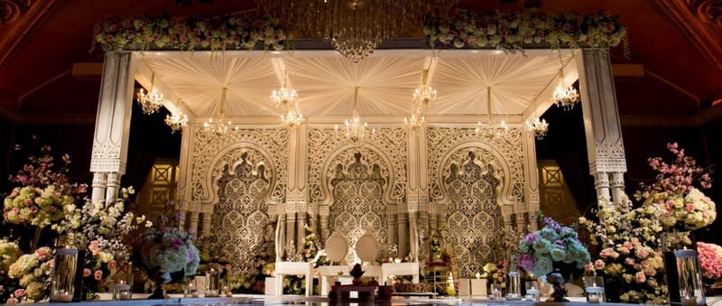 Ivory and gold fiberglass mandap with carved jali panels and crystal chandeliers, set for a ballroom ceremony